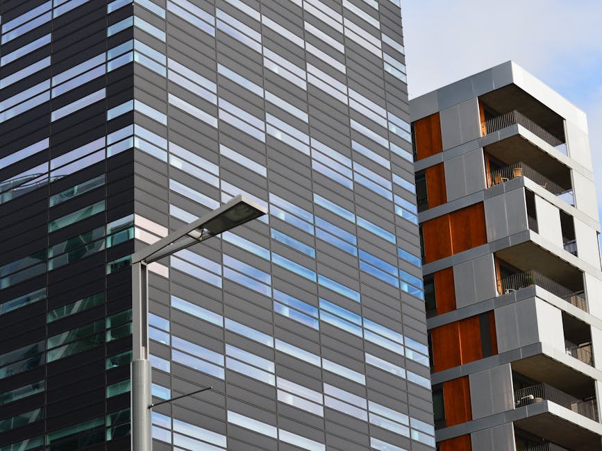 Low angle view of a modern glass office building and residential structure in daylight